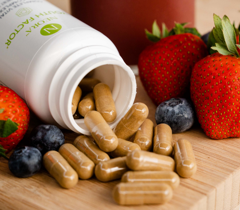 Neora Youth Factor® Vitality Complex bottle and pills shown pictured with berries